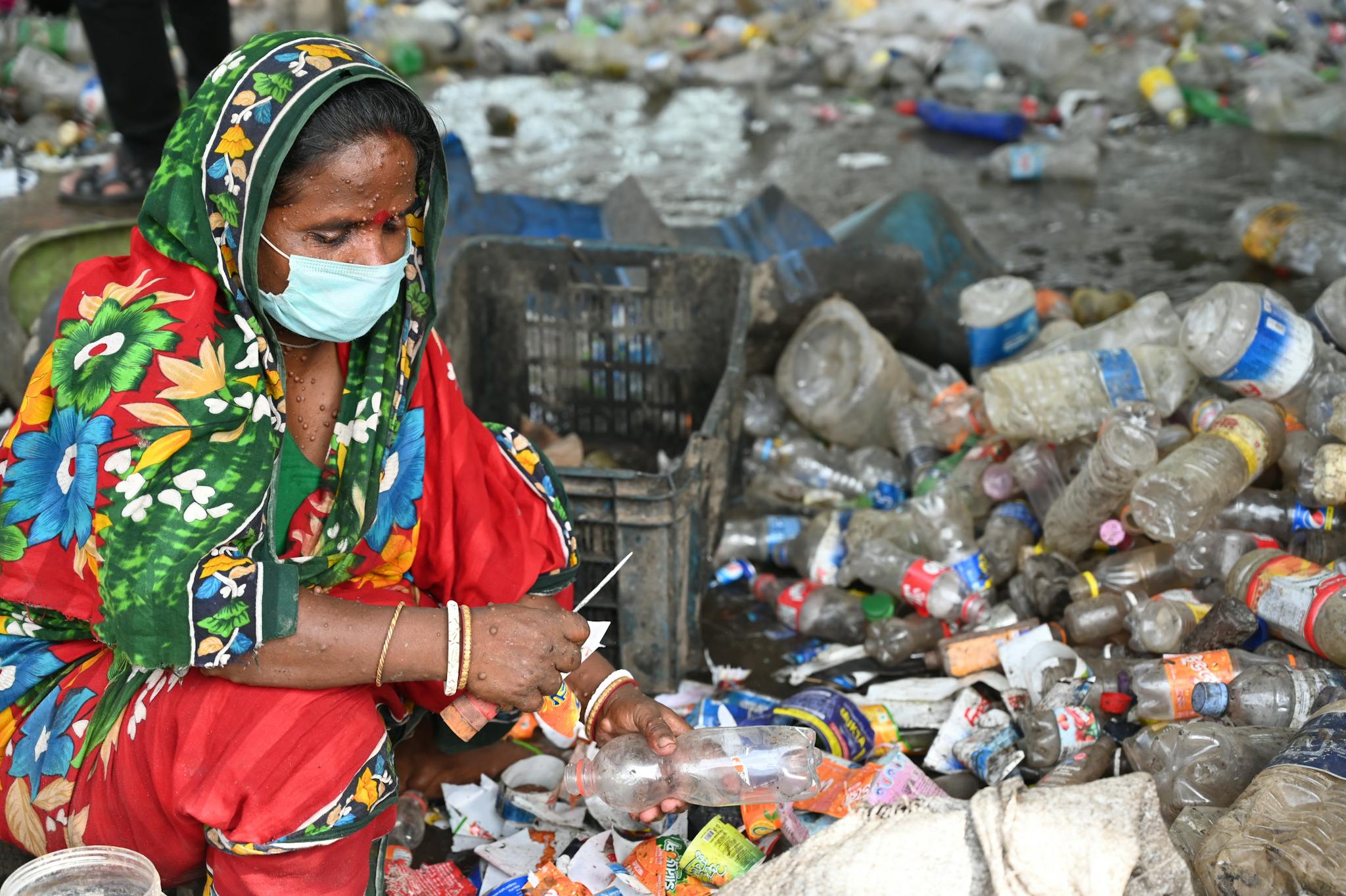 A woman in Chattogram sorts plastic bottles, highlighting recycling efforts and waste management.